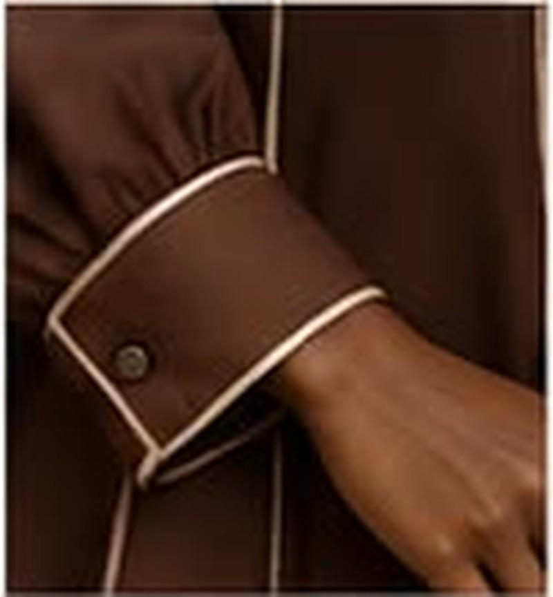 Buttoned and narrow, against a full gathered sleeve.